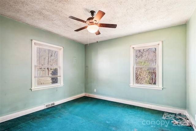 carpeted spare room with a textured ceiling, ceiling fan, visible vents, and baseboards