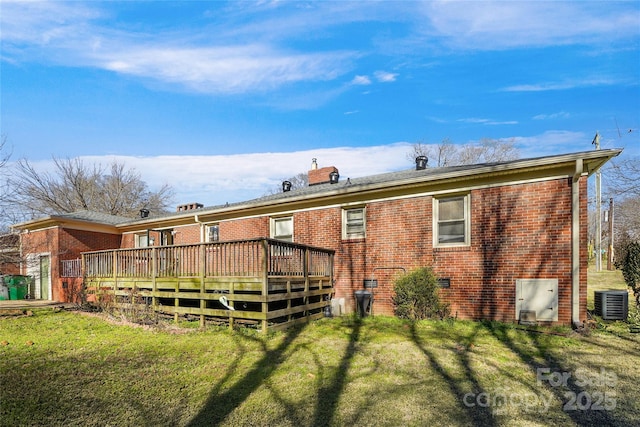 back of property featuring a deck, brick siding, a lawn, and central AC unit