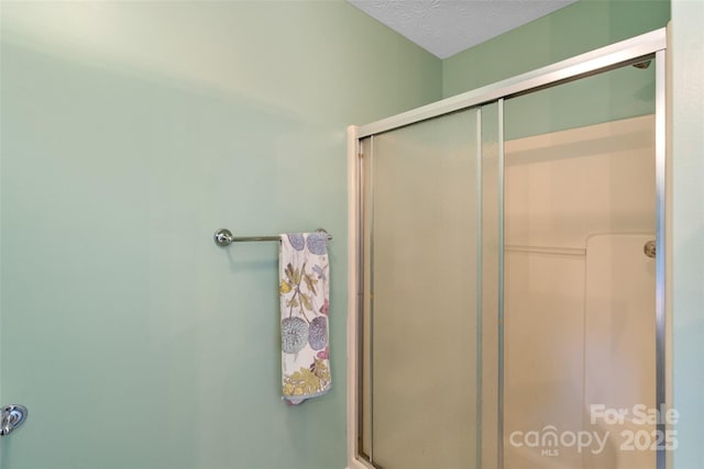 bathroom with a shower with door and a textured ceiling