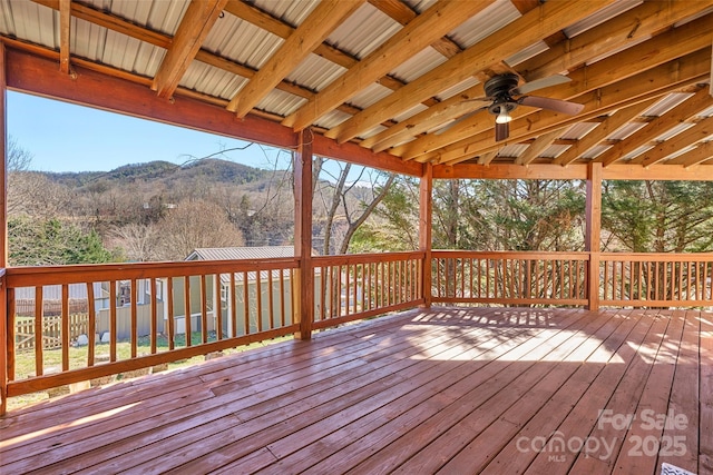 wooden terrace featuring a wooded view, a mountain view, and a ceiling fan