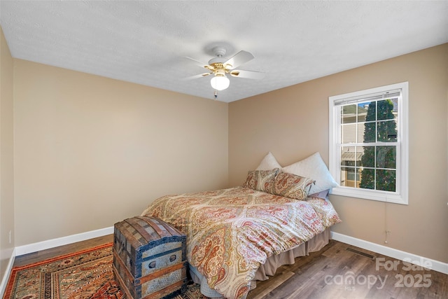 bedroom featuring a textured ceiling, wood finished floors, visible vents, and baseboards