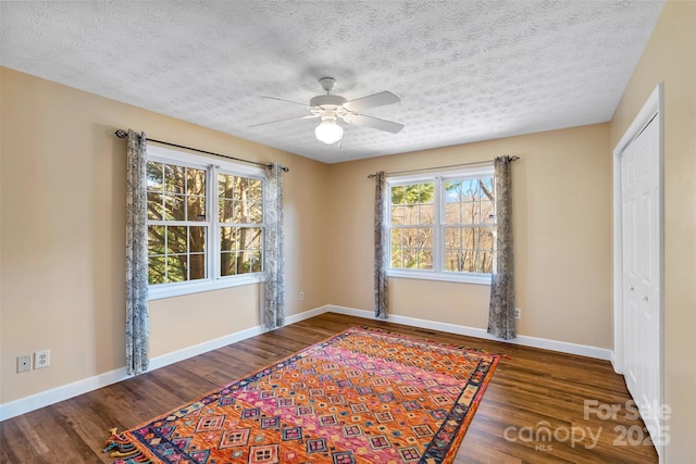 unfurnished room with a textured ceiling, baseboards, and wood finished floors