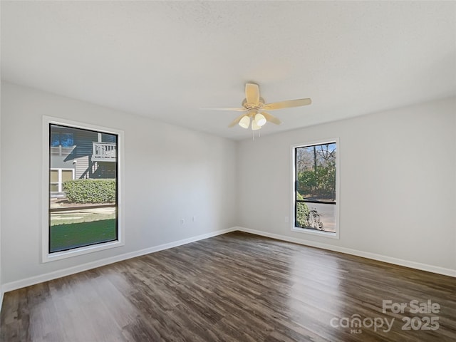 empty room featuring ceiling fan, baseboards, and dark wood-type flooring