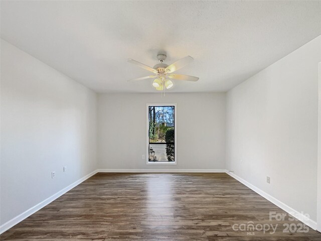 unfurnished room featuring dark wood-type flooring, a ceiling fan, and baseboards