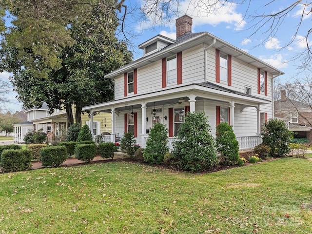 view of front facade featuring covered porch, a chimney, and a front yard