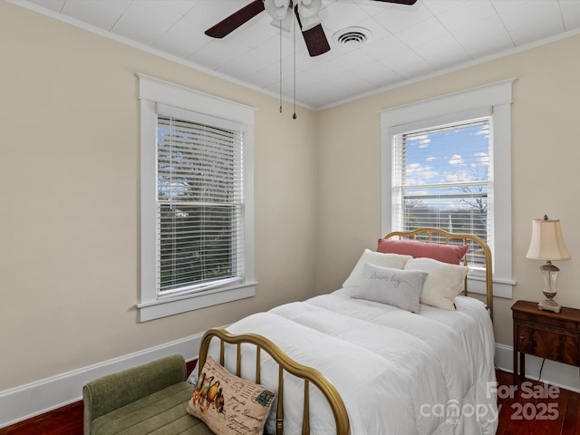 bedroom featuring ornamental molding, visible vents, baseboards, and wood finished floors