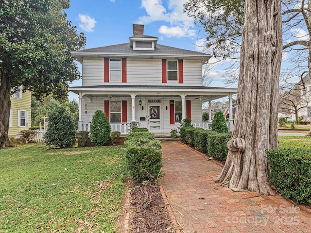 traditional style home with covered porch, a chimney, and a front yard