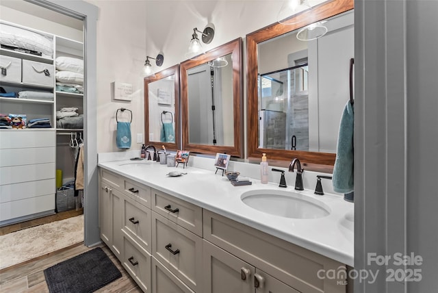 full bathroom featuring double vanity, a sink, a shower stall, and a spacious closet