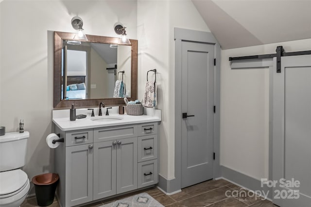 bathroom with toilet, vaulted ceiling, vanity, and baseboards