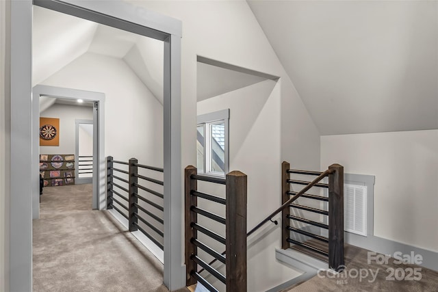 interior space featuring carpet, vaulted ceiling, and an upstairs landing