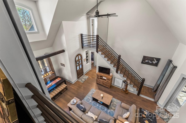 living room featuring stairs, wood finished floors, a towering ceiling, and a ceiling fan