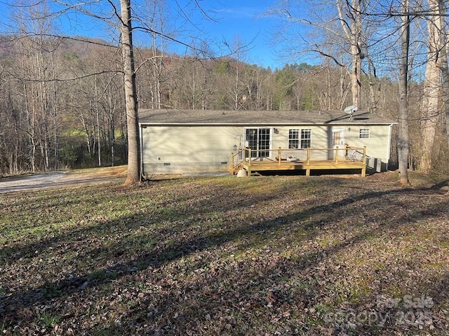 manufactured / mobile home with a deck, crawl space, and a view of trees