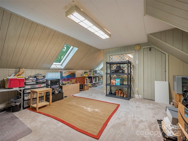 additional living space with lofted ceiling with skylight, carpet flooring, and wooden walls