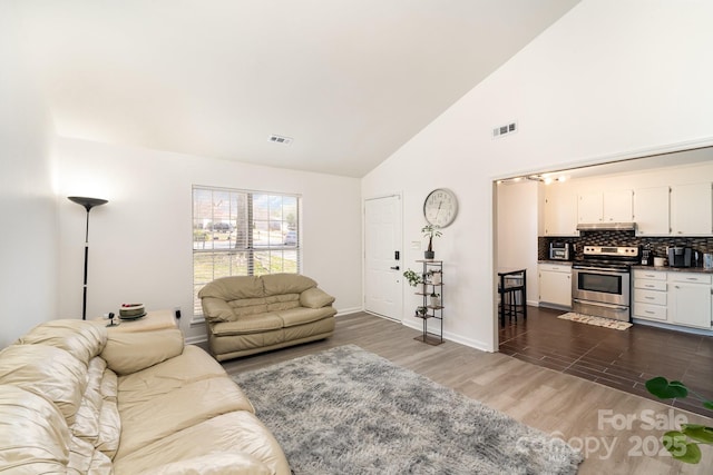 living room with dark wood-type flooring, visible vents, and high vaulted ceiling