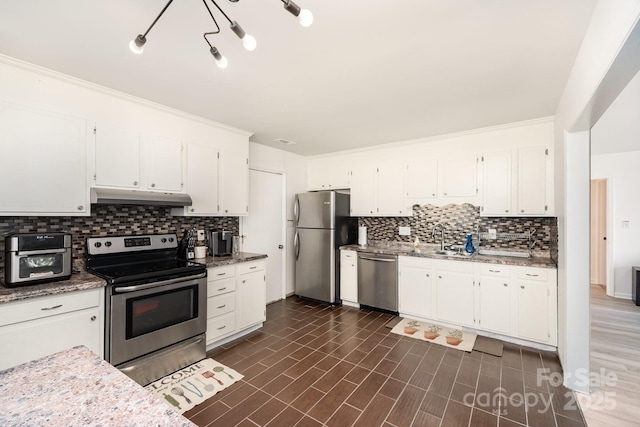 kitchen with under cabinet range hood, appliances with stainless steel finishes, white cabinets, and a sink