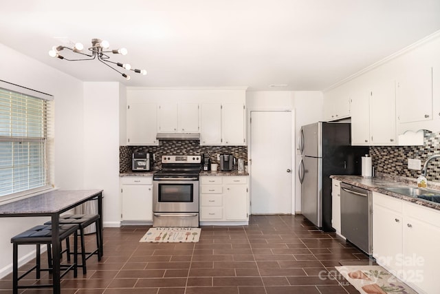 kitchen featuring decorative backsplash, white cabinets, appliances with stainless steel finishes, under cabinet range hood, and a sink