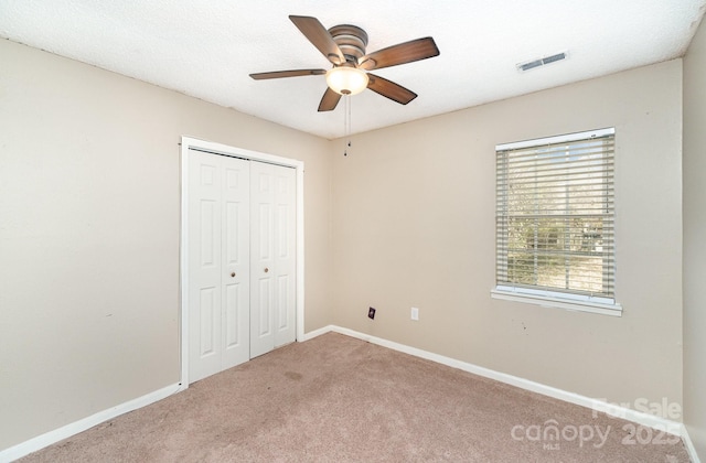 unfurnished bedroom featuring carpet floors, baseboards, visible vents, and a closet