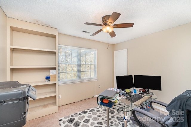 office space featuring a textured ceiling, carpet flooring, visible vents, and a ceiling fan