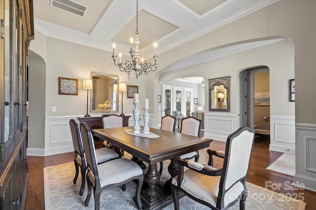 dining area with arched walkways, dark wood-style flooring, and visible vents