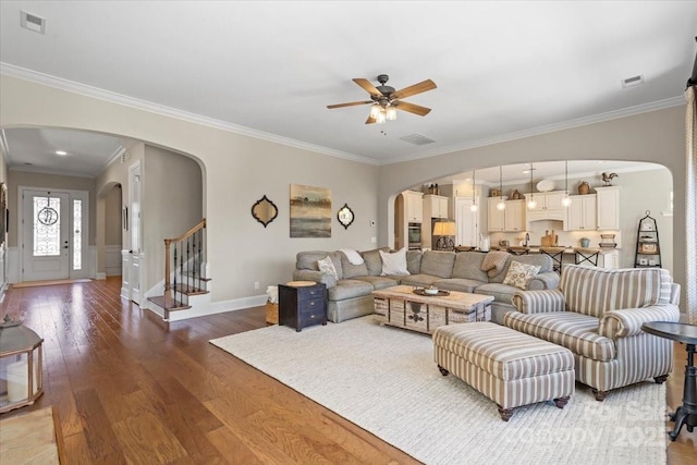 living area featuring visible vents, arched walkways, and wood finished floors