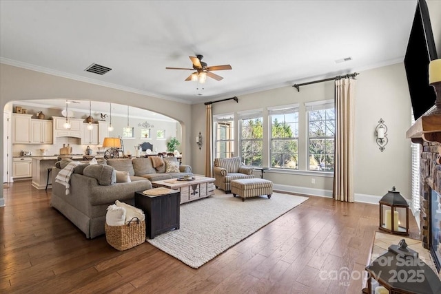 living area with arched walkways, a fireplace, dark wood-style floors, and visible vents