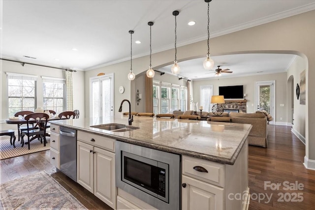 kitchen featuring appliances with stainless steel finishes, arched walkways, dark wood finished floors, and a sink