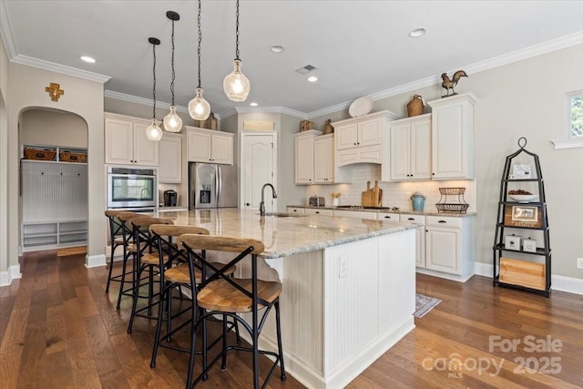 kitchen featuring stainless steel appliances, arched walkways, dark wood-type flooring, and a sink