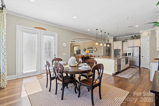 dining area featuring arched walkways, dark wood-type flooring, recessed lighting, and crown molding