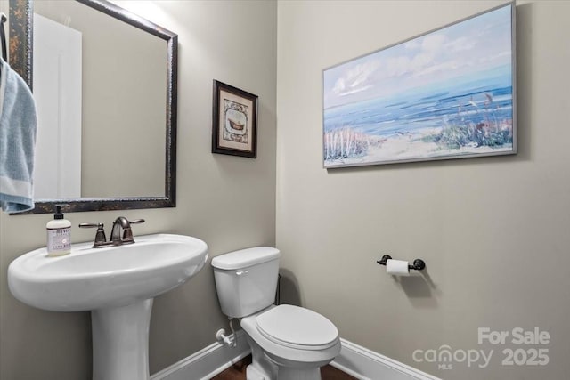 bathroom featuring toilet, baseboards, and a sink