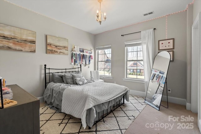 bedroom with light carpet, baseboards, visible vents, and a chandelier