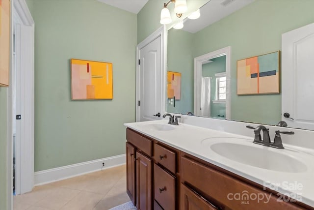 bathroom with double vanity, tile patterned flooring, baseboards, and a sink