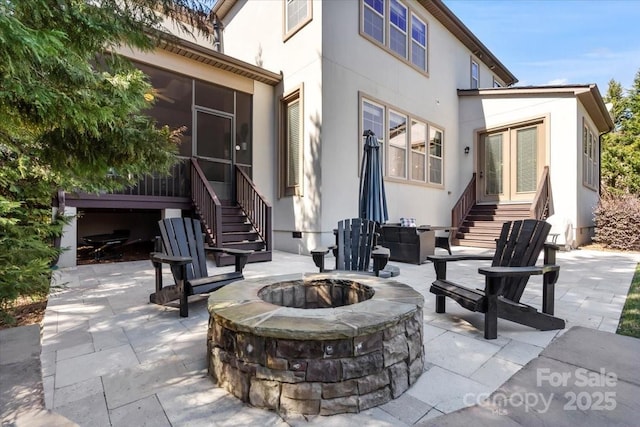 view of patio / terrace featuring entry steps, a sunroom, and a fire pit