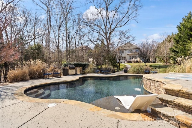 view of swimming pool featuring fence, an outdoor kitchen, a fenced in pool, and a patio