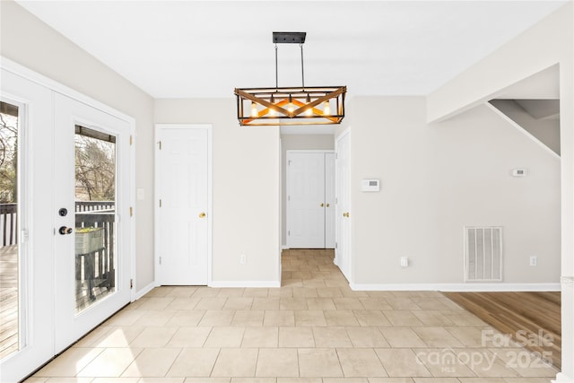 unfurnished dining area featuring french doors, visible vents, and baseboards