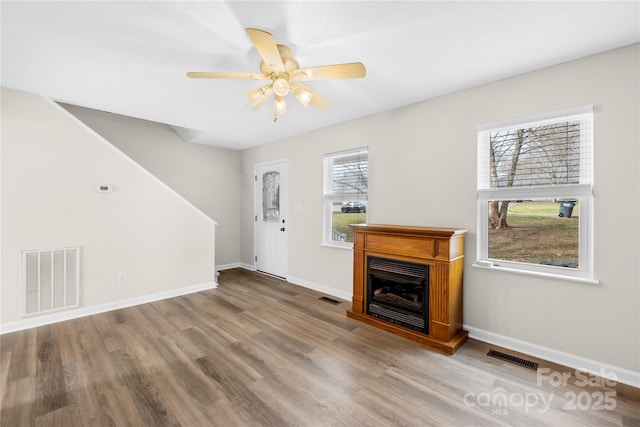 unfurnished living room featuring visible vents, a fireplace, and wood finished floors