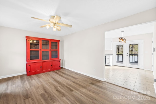 empty room featuring ceiling fan, wood finished floors, and baseboards