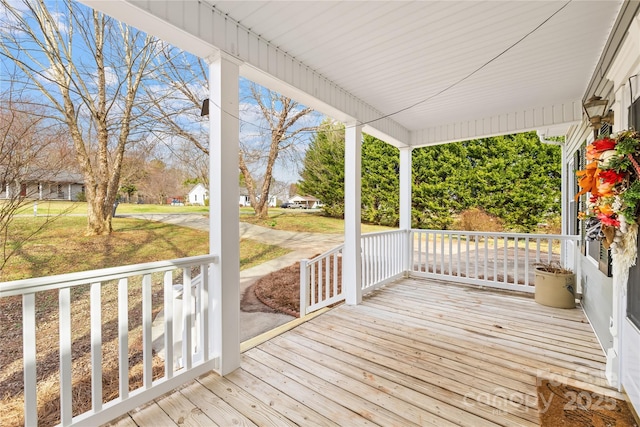 wooden deck with covered porch and a lawn