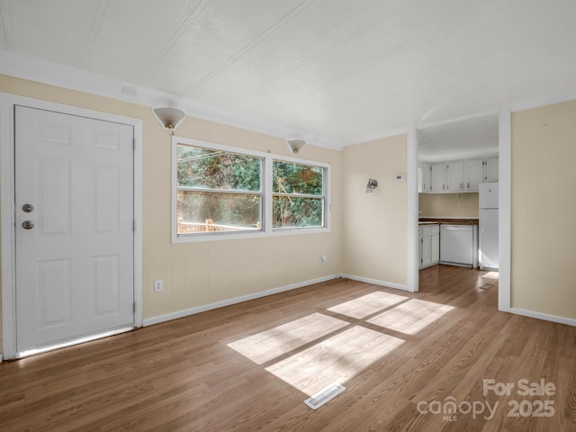 unfurnished living room with baseboards, visible vents, and wood finished floors