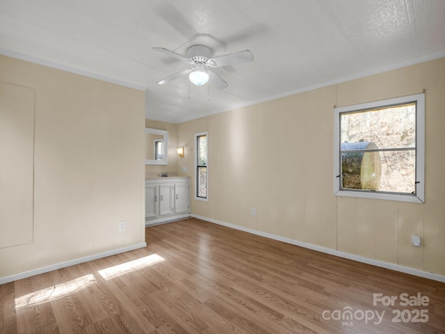 unfurnished room with ceiling fan, plenty of natural light, baseboards, and light wood-style floors