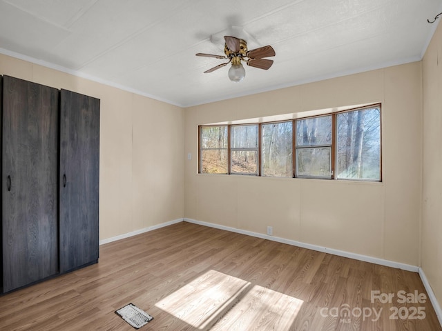 unfurnished bedroom with crown molding, wood finished floors, a ceiling fan, and baseboards