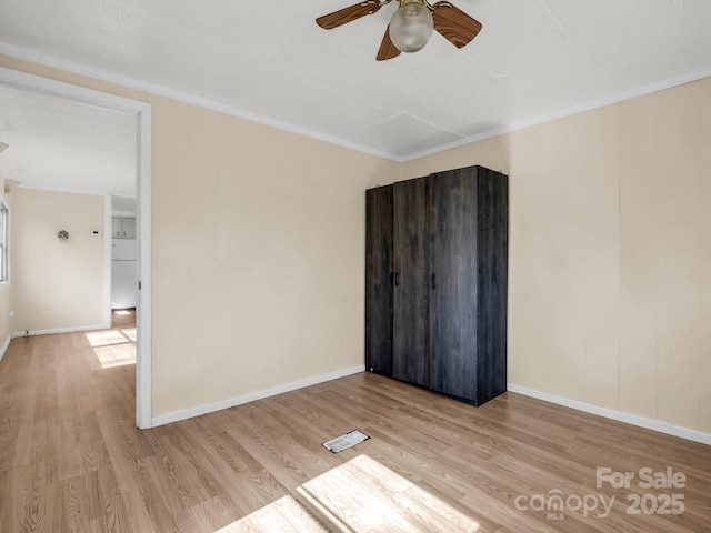 unfurnished room featuring ceiling fan, crown molding, baseboards, and wood finished floors