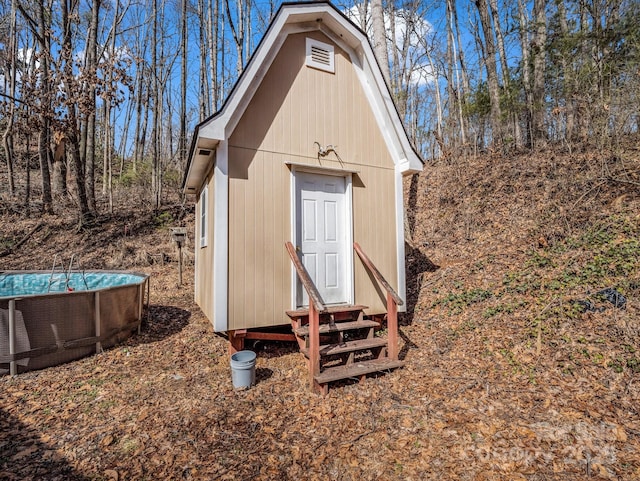 view of outbuilding with entry steps, an outdoor pool, cooling unit, and an outdoor structure