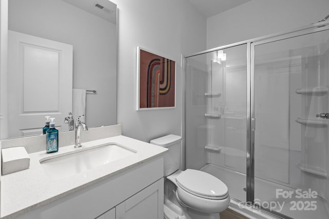 bathroom featuring visible vents, a stall shower, vanity, and toilet