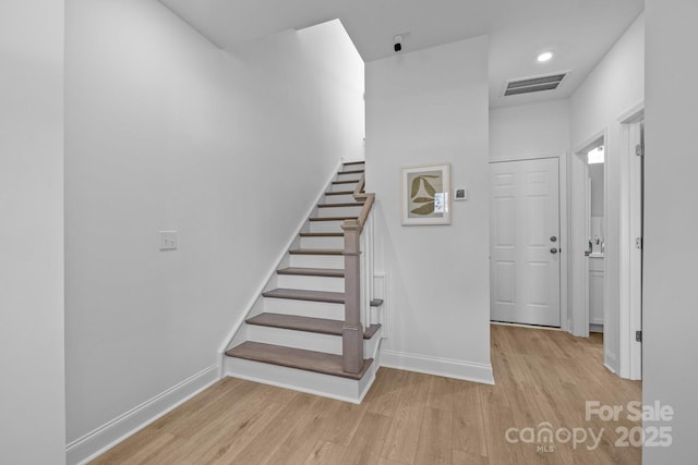 stairway featuring wood finished floors, visible vents, and baseboards