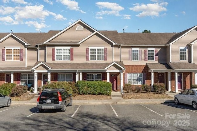 townhome / multi-family property with uncovered parking and brick siding