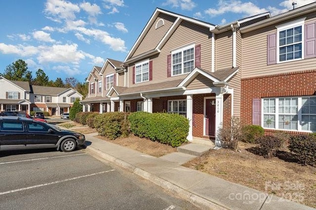 view of property featuring uncovered parking, a residential view, and brick siding