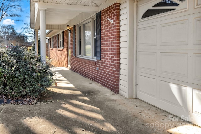 view of home's exterior featuring a garage, brick siding, and a porch