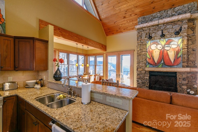 kitchen featuring open floor plan, a peninsula, a fireplace, and a sink