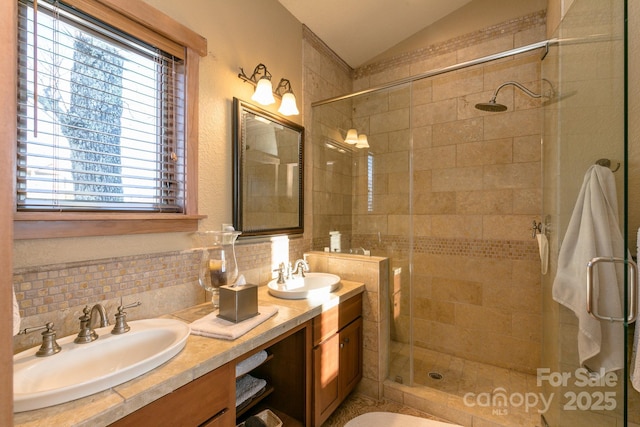 full bath featuring vaulted ceiling, double vanity, a stall shower, and a sink