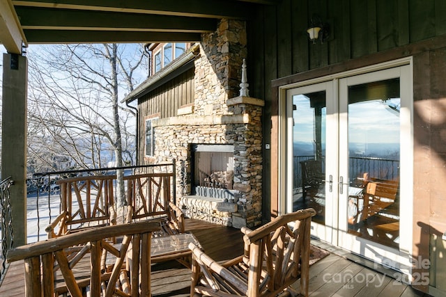 wooden terrace featuring french doors and an outdoor stone fireplace